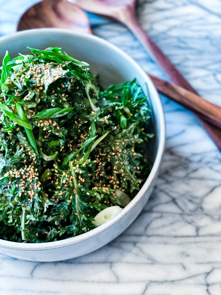 Kale Salad with Sweet Tahini Dressing in white bowl on marble counter top